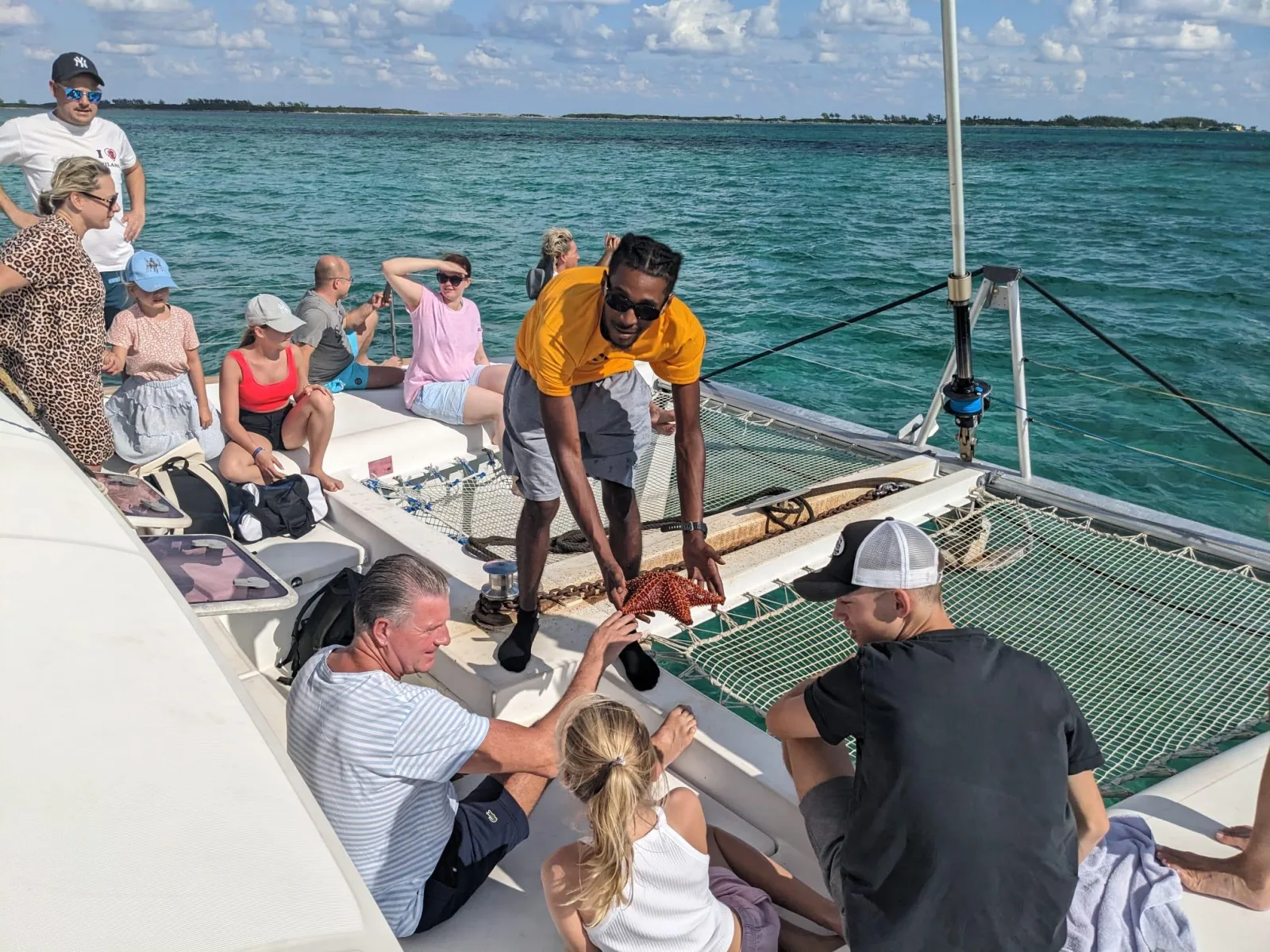 Guests gathered on the catamaran's foredeck as a crew member hands round drinks