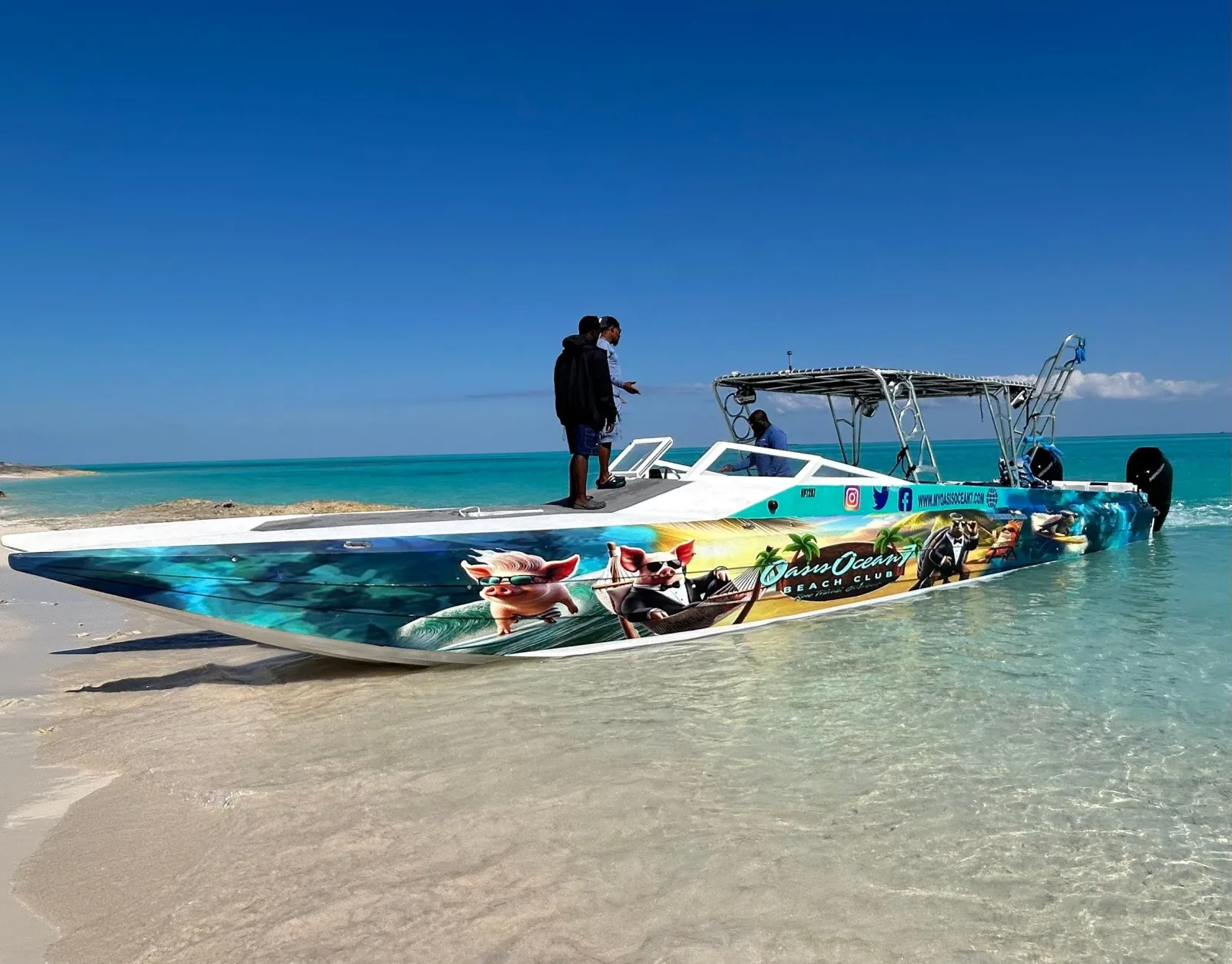 A powerboat moored off a sandbar with the beach club buildings along the shore