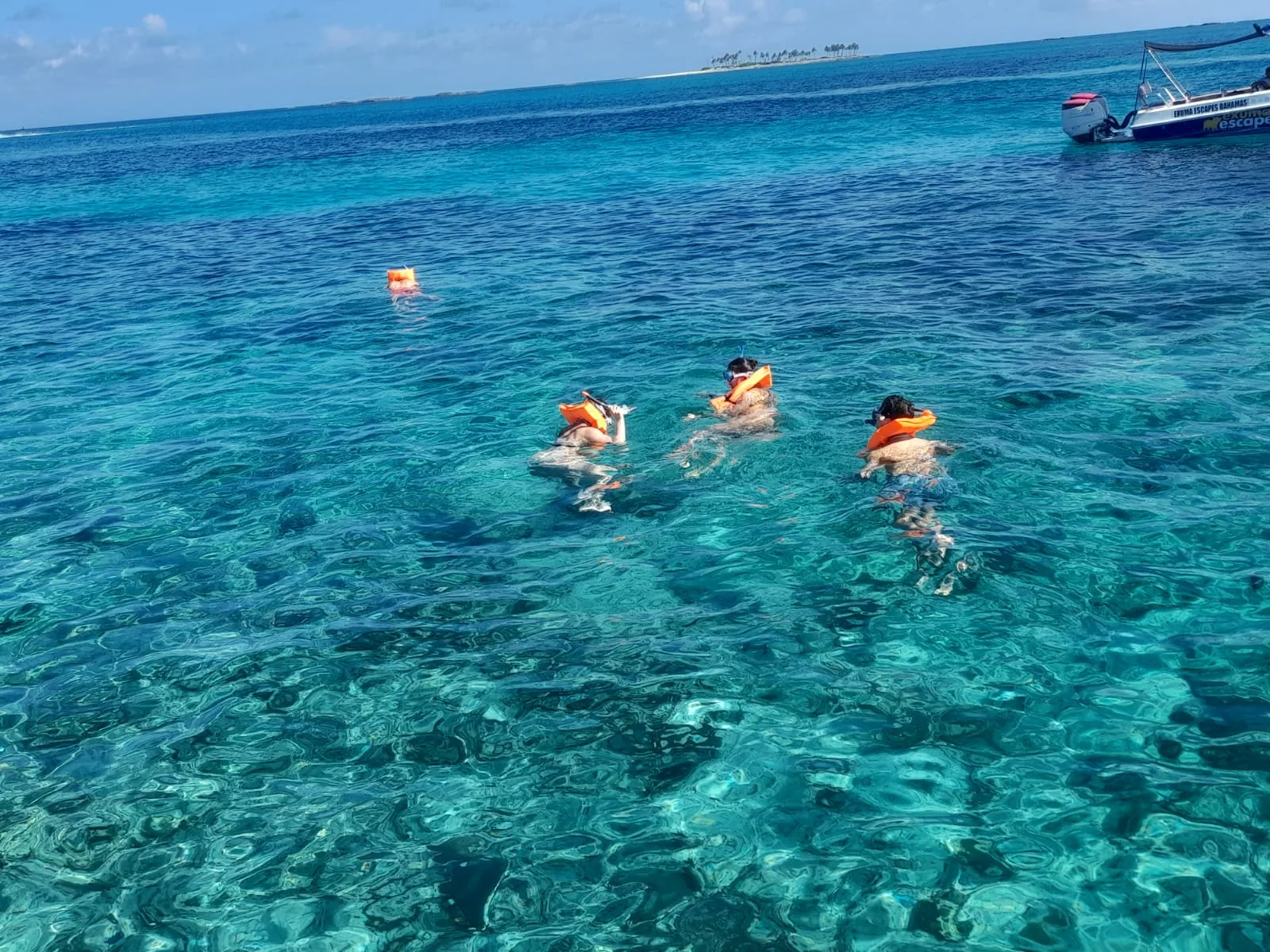 Snorkellers spread out over the reef in deep blue water off Green Cay