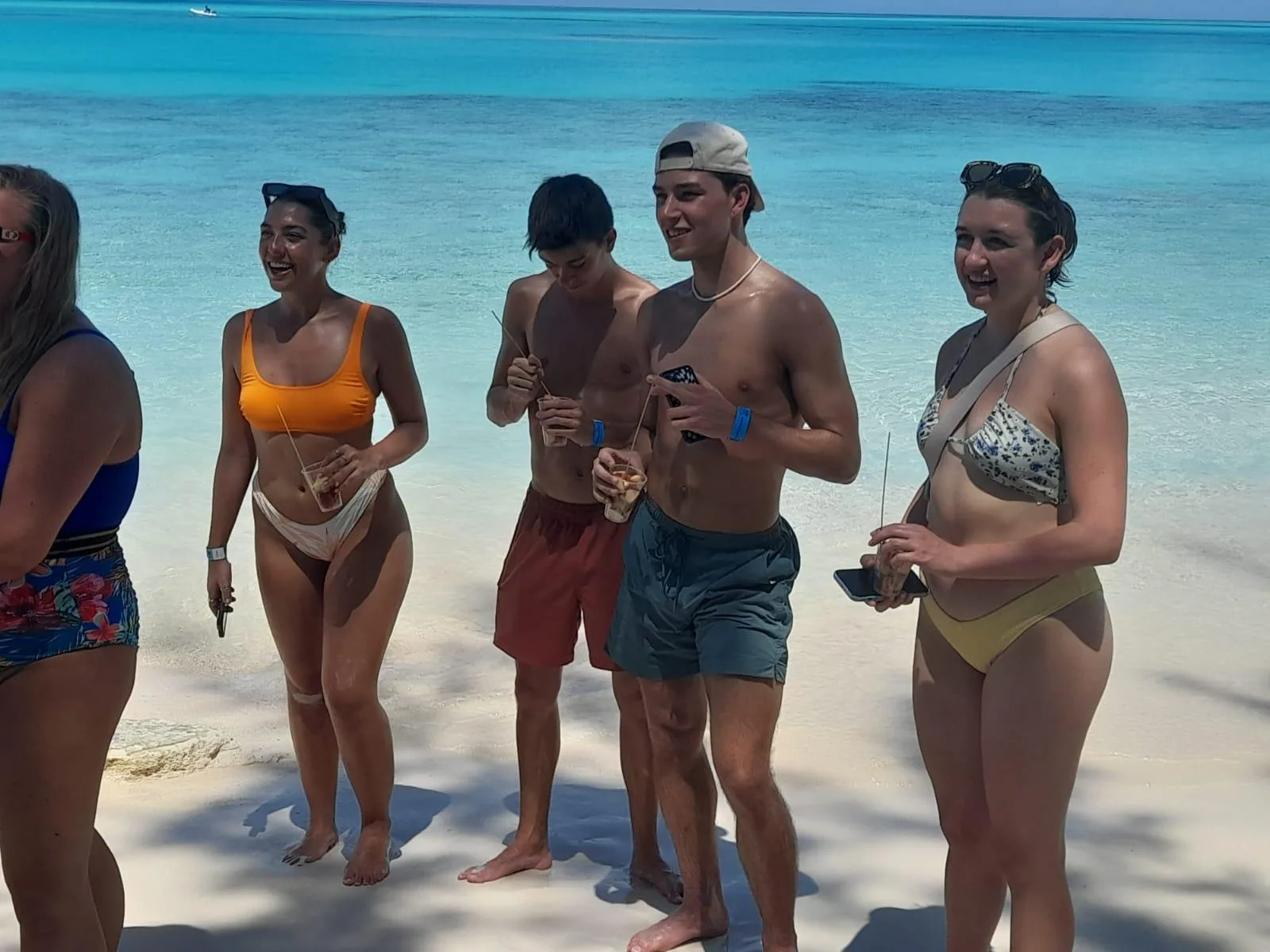 The charter group standing in the shallows with drinks at the pig beach stop
