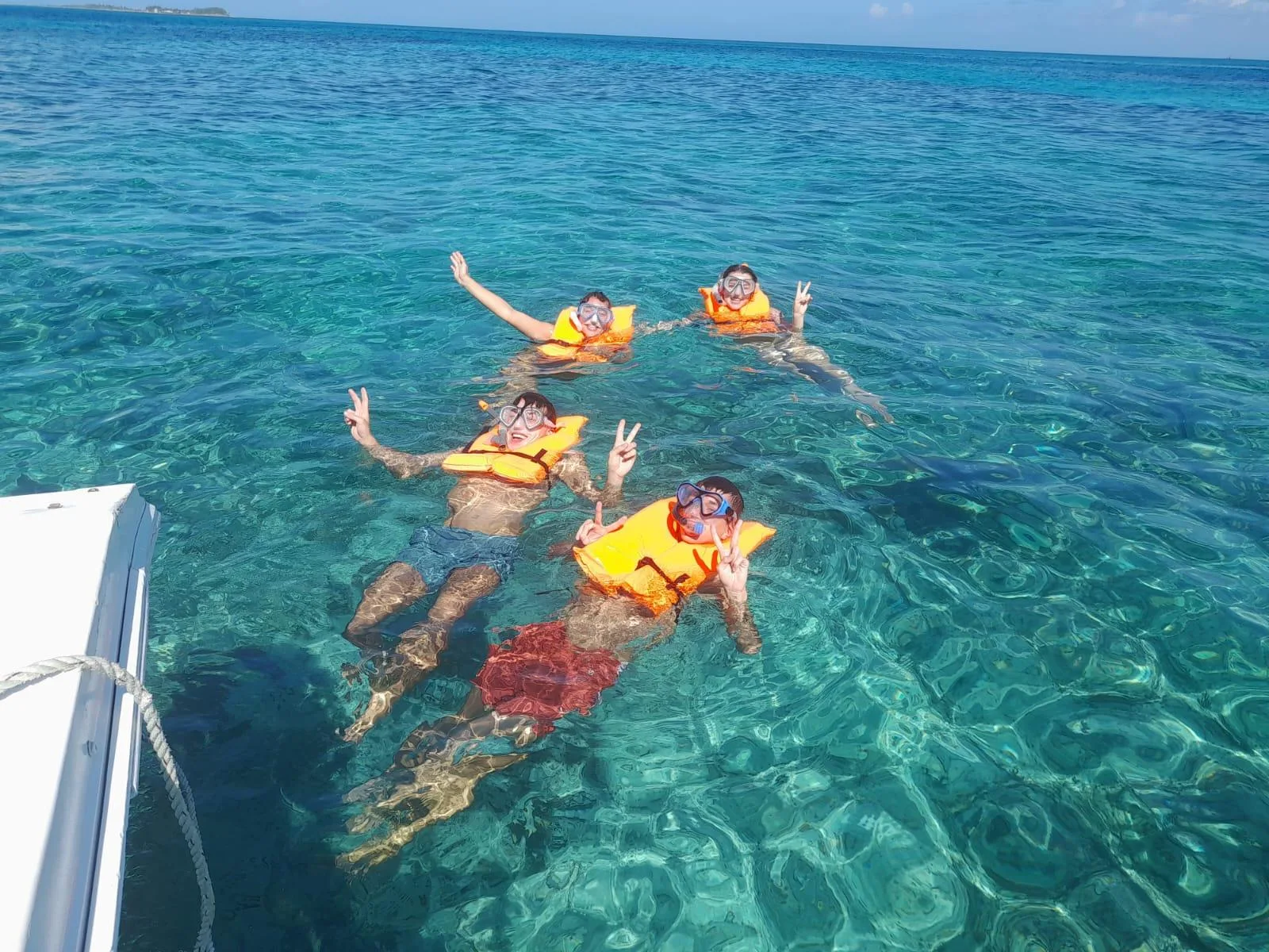 Snorkellers in life vests floating together over the reef beside the boat