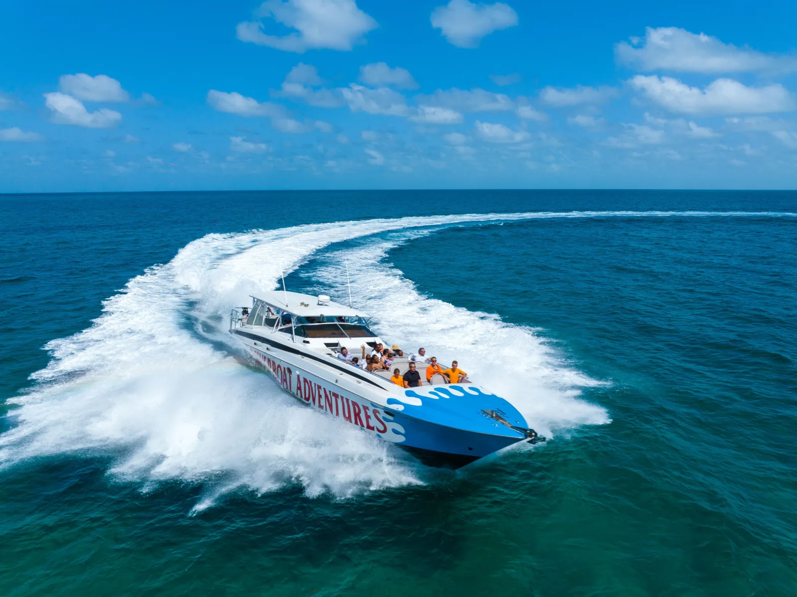 The blue Powerboat Adventures jet boat at speed, seen from behind on the crossing